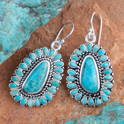 Turquoise and silver earrings on a textured stone background