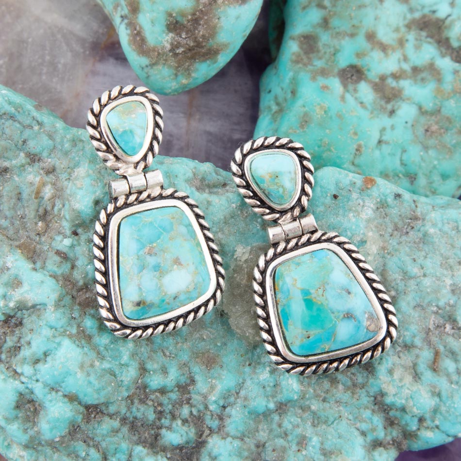 Turquoise earrings with silver frames on a turquoise stone background