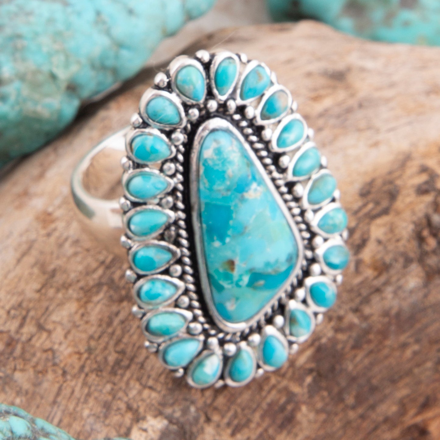 Turquoise stone ring with silver setting on a wooden surface