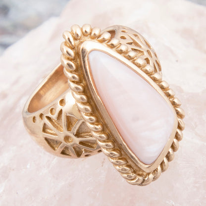 Gold ring with a white stone on a textured surface