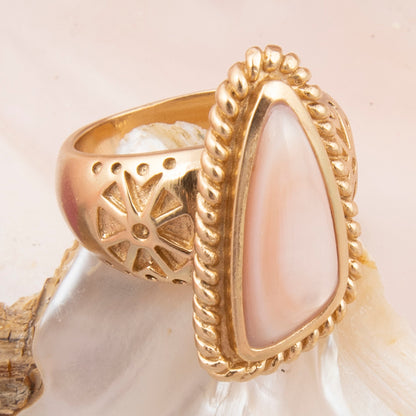 Gold ring with a teardrop-shaped pearl on a shell background