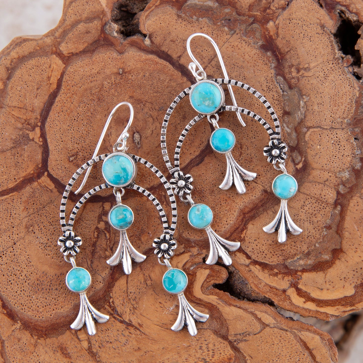Turquoise and silver earrings on a wooden surface
