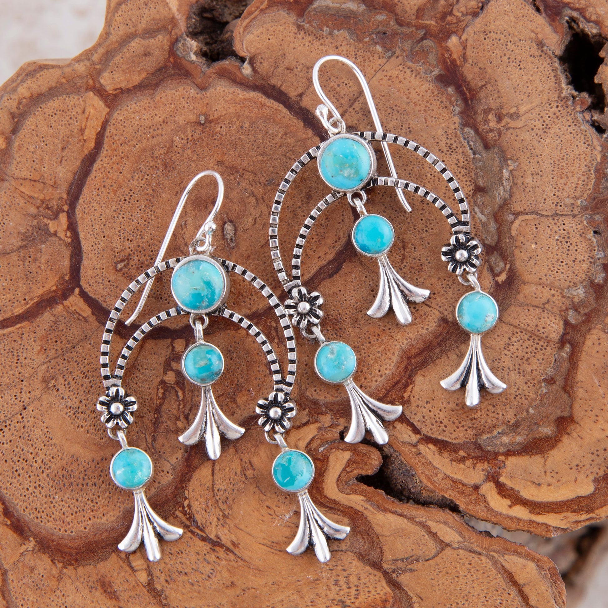 Turquoise and silver earrings on a wooden surface