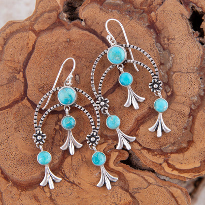 Turquoise and silver earrings on a wooden surface