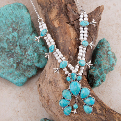 Turquoise and silver beaded necklace on a natural background with turquoise stones.