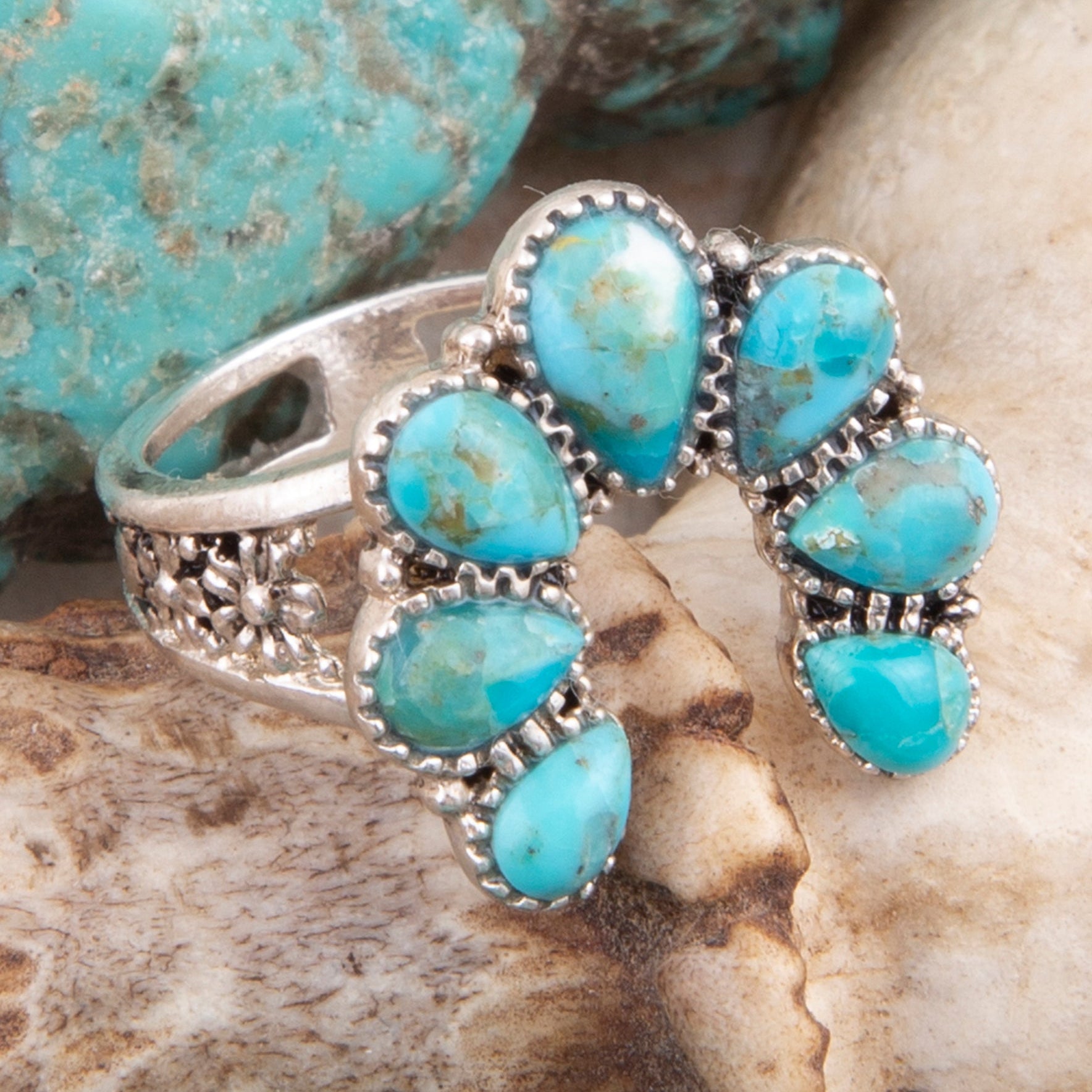 Turquoise stone ring with silver band on a natural stone background