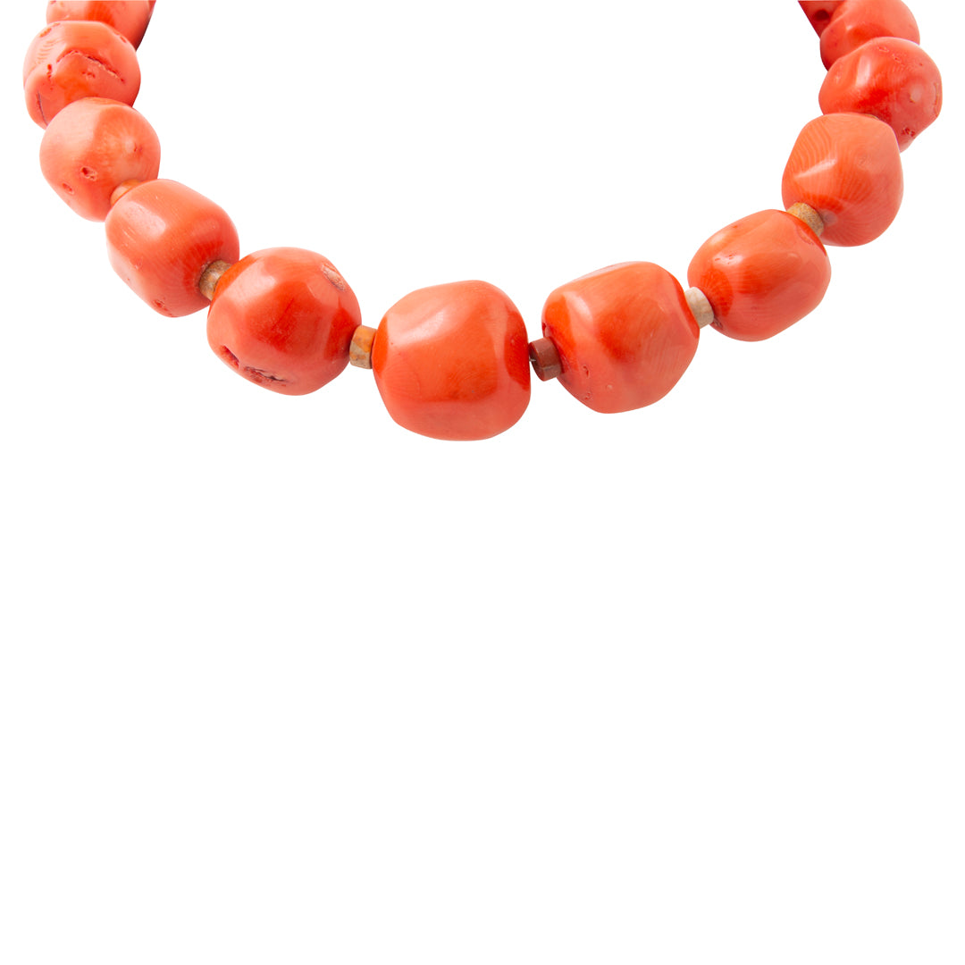 A close-up of a beaded necklace made of chunky, rounded terracotta-orange beads, shown against a plain white background.