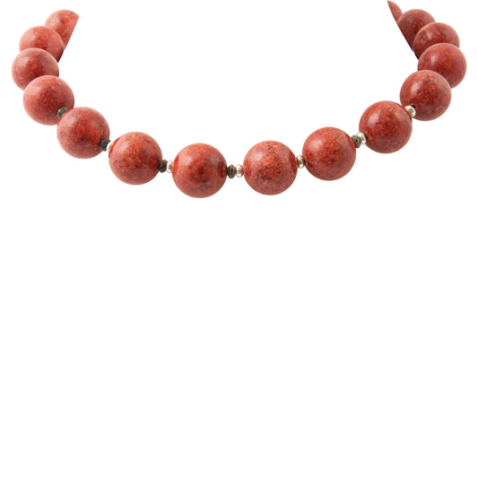 A strand of polished round red beads with small metallic spacer details, arranged in a curved line against a solid white background.