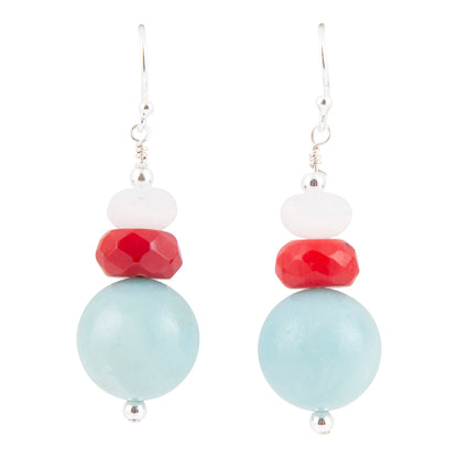 A pair of silver dangle earrings featuring a stacked bead design with a large light blue bead, a faceted red bead, a small white bead, and a silver hook on a solid white background.