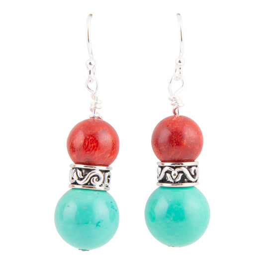 A pair of dangle earrings featuring a red stone bead, an ornate silver spacer, and a larger turquoise green bead, suspended from silver fishhook wires on a white background.