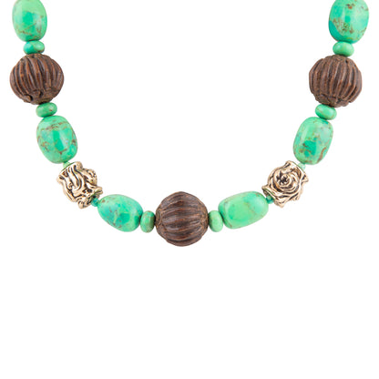 A beaded necklace featuring textured green turquoise-like beads, dark brown ribbed beads, and two antique gold rose-shaped spacers on a plain white background.