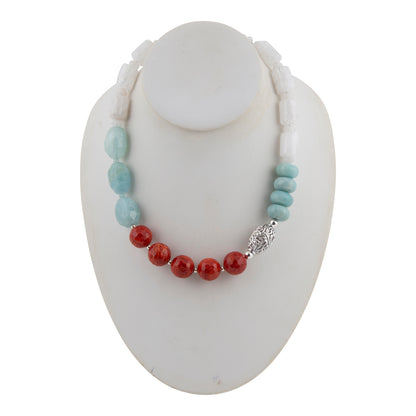A beaded necklace displayed on a white mannequin bust, featuring light blue turquoise-like beads, red coral-like beads, and a silver filigree accent.