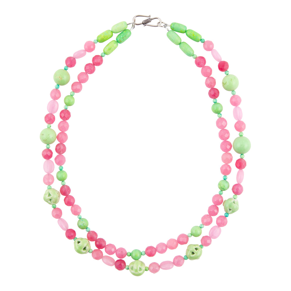 A double-strand beaded necklace featuring alternating light green and pink beads, with larger light green oval beads and small carved skull accents, displayed on a clean white background.