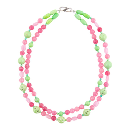 A double-strand beaded necklace featuring alternating light green and pink beads, with larger light green oval beads and small carved skull accents, displayed on a clean white background.