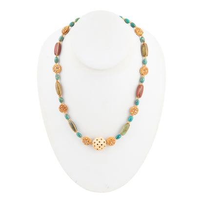 A beaded necklace displayed on a white mannequin bust, featuring turquoise blue beads, brown stone beads, and textured gold-tone metal beads with a central gold-tone medallion.