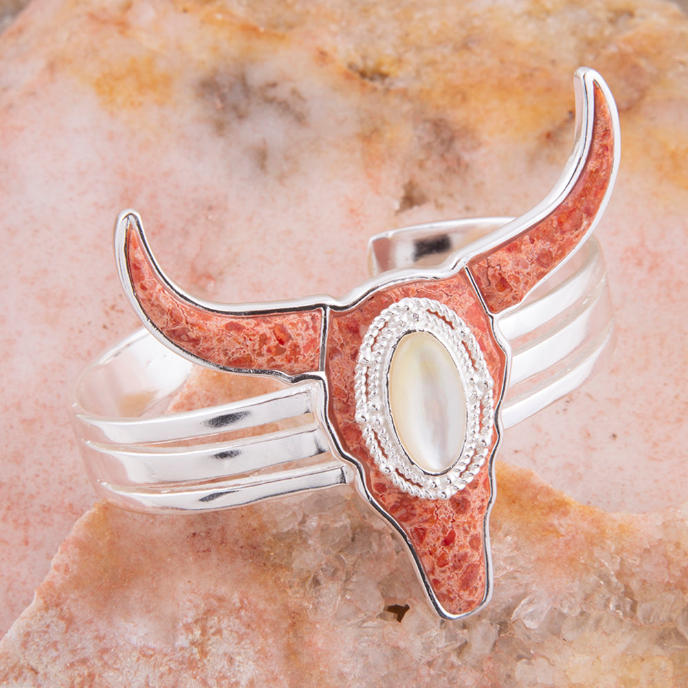 Silver and red longhorn cattle skull bracelet on a stone background