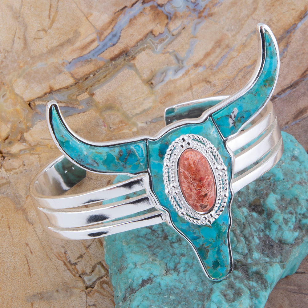 Silver and turquoise bull head cuff bracelet on a stone background