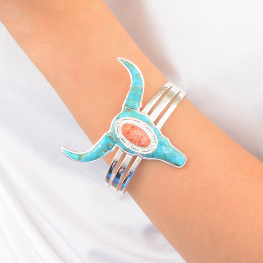 Turquoise and coral bangle on a wrist against a white background