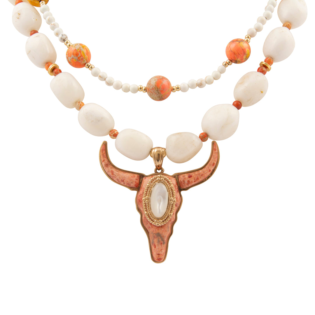 Necklace with white beads and a bull head pendant on a white background