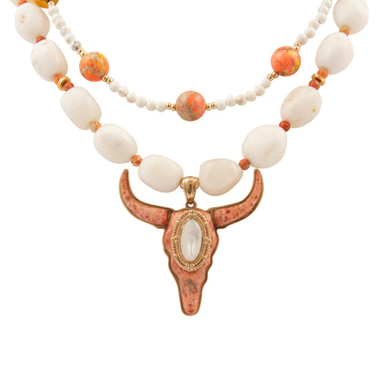 Necklace with white beads and a bull head pendant on a white background
