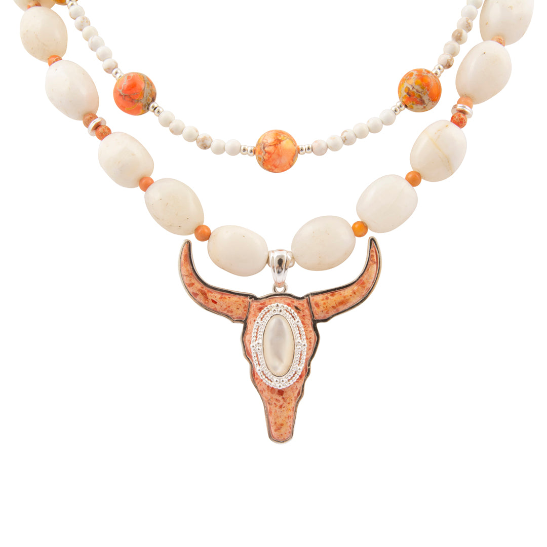 Necklace with large bull head pendant and white and orange beads on a white background