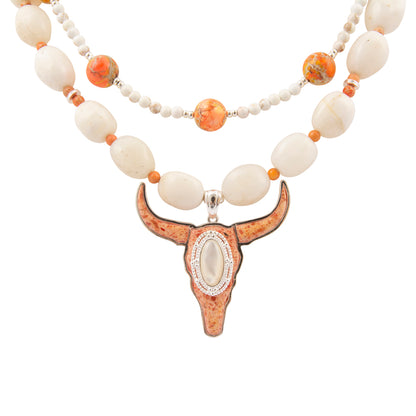Necklace with large bull head pendant and white and orange beads on a white background