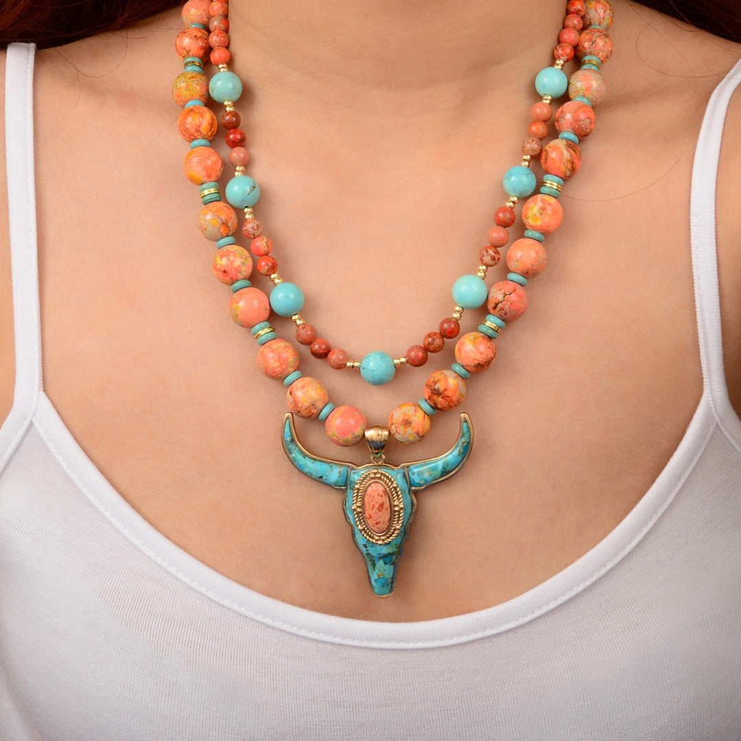 Necklace with colorful beads and a turquoise pendant on a person wearing a white tank top.