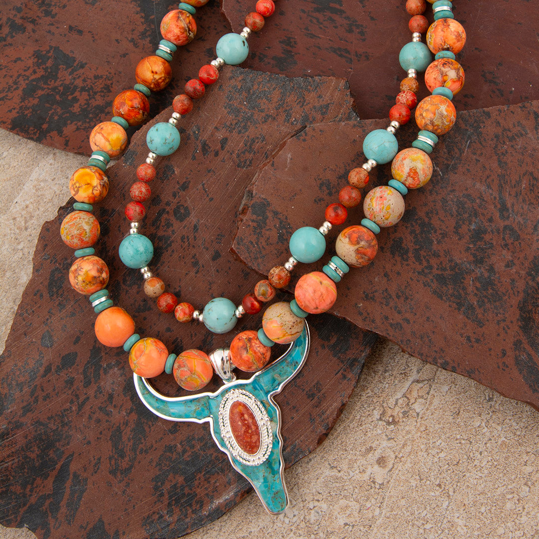 Necklace with multicolored beads and a large pendant on a textured surface
