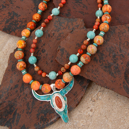 Necklace with multicolored beads and a large pendant on a textured surface