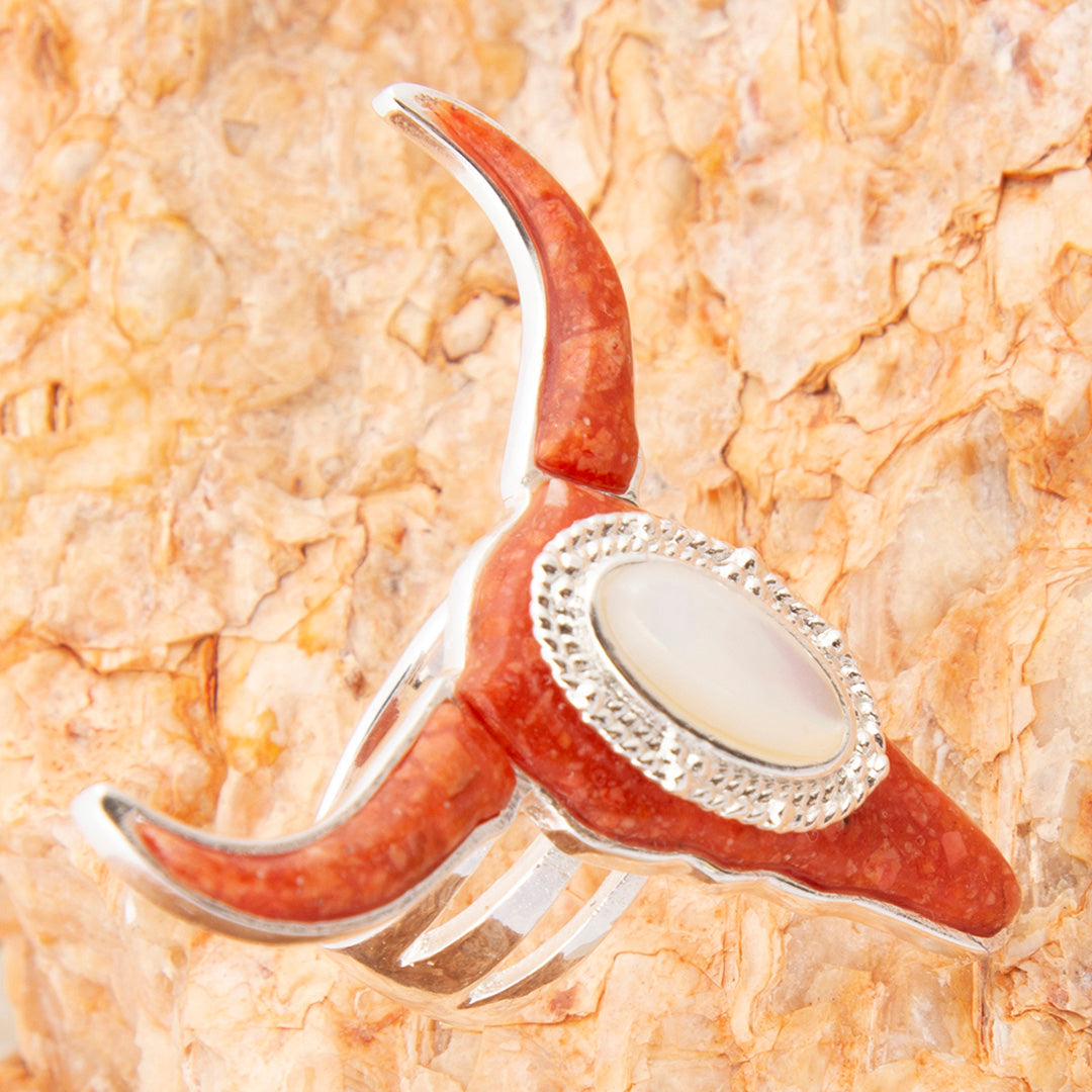 Coral and silver ring with a central stone on a textured coral background