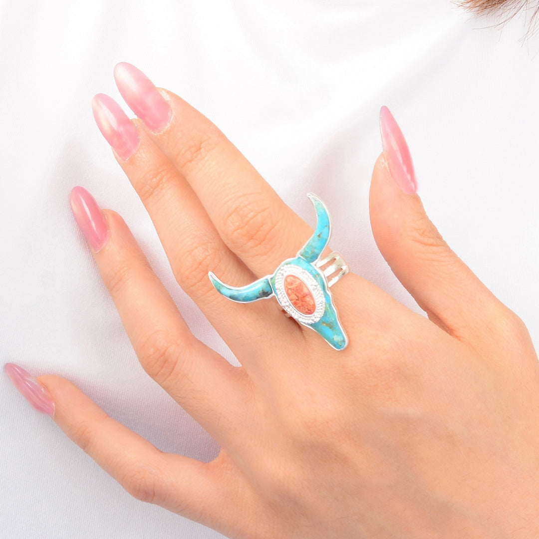 Hand wearing a turquoise ring with a pink nail design on a white background