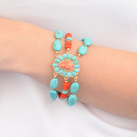 Turquoise and coral beaded bracelet on a wrist against a white background