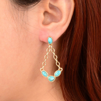 Close-up of an ear wearing a turquoise earring with gold chain