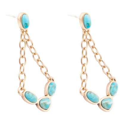 Pair of gold earrings with turquoise stones on a white background