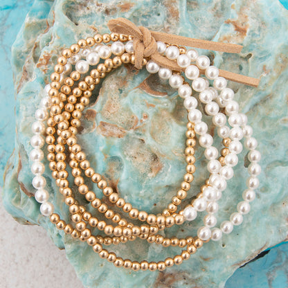 Gold and white beaded bracelets on a textured blue surface