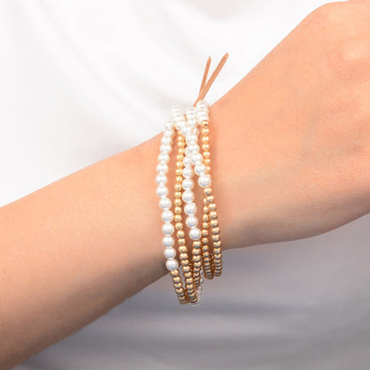 Three pearl bracelets on a wrist against a neutral background