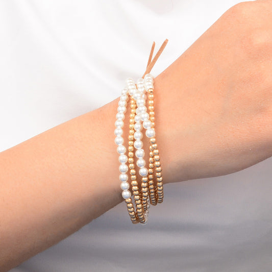 Three pearl bracelets on a wrist against a neutral background