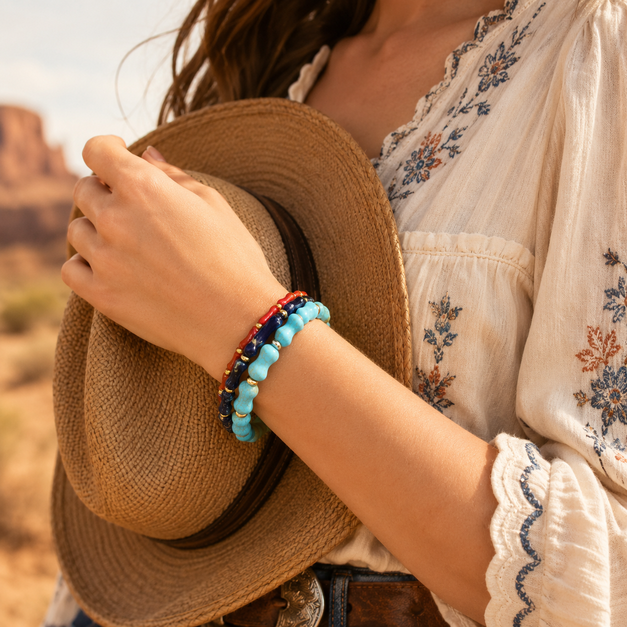 Person holding a straw hat with a scenic desert background
