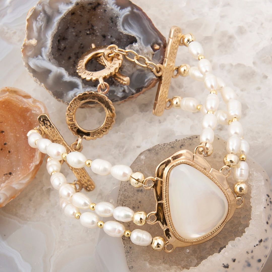 Pearl bracelet with gold accents on a textured stone surface
