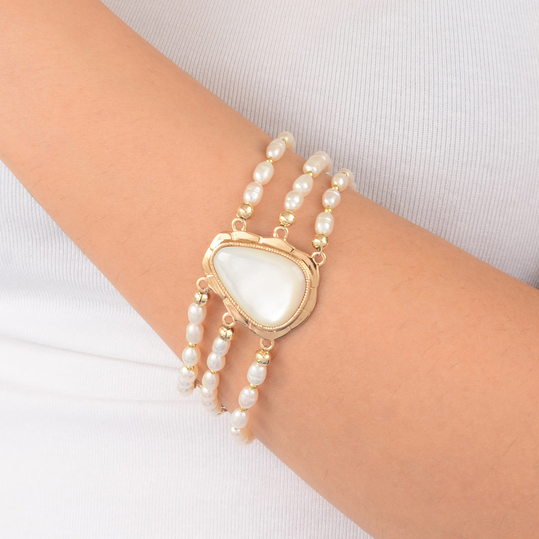 Pearl bracelet with a heart-shaped white stone on a wrist against a white background