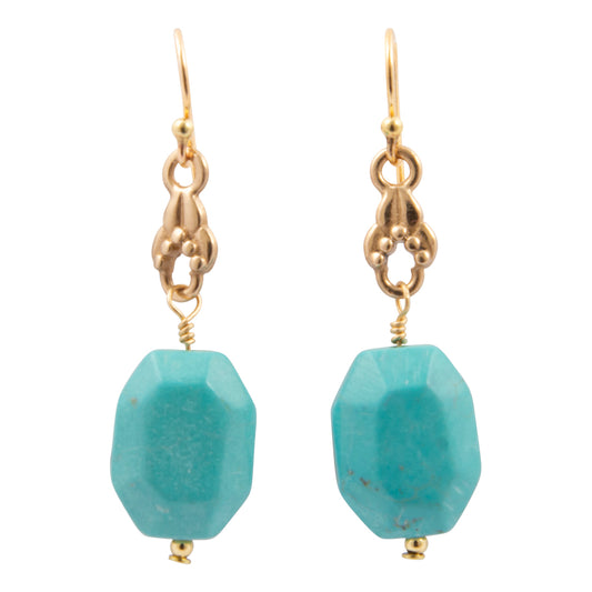 Gold earrings with turquoise beads on a white background