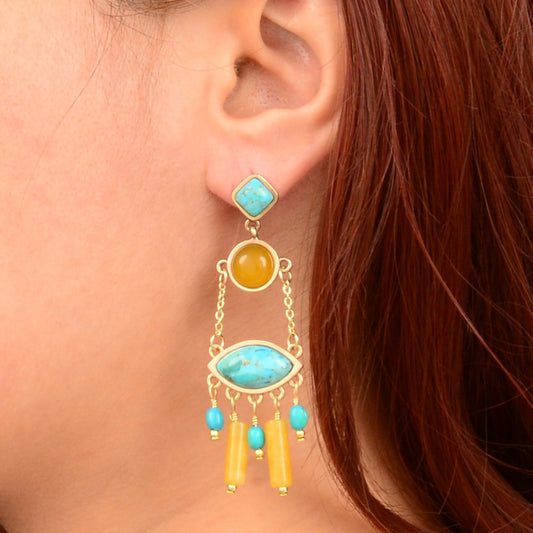 Close-up of an ear wearing a turquoise and yellow earring with dangling beads.