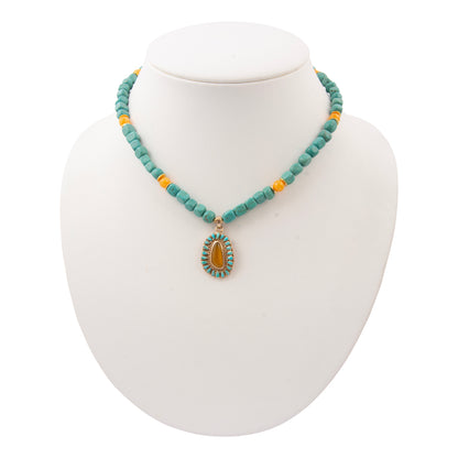 Turquoise beaded necklace with a yellow pendant on a white mannequin bust.