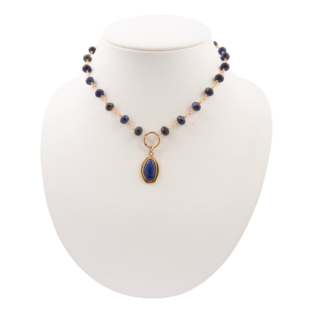 Necklace with blue beads and a gold pendant on a white mannequin bust.