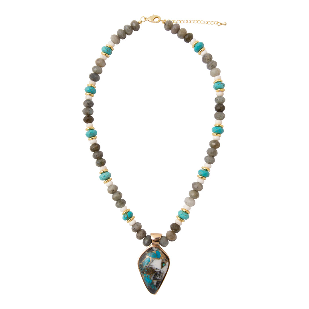 A beaded necklace featuring gray and olive stone beads with turquoise accents, separated by small gold spacer beads, and a large teardrop-shaped turquoise and gray stone pendant in a gold frame.