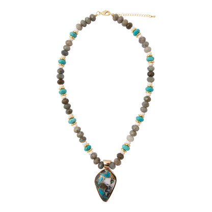 A beaded necklace featuring gray and olive stone beads with turquoise accents, separated by small gold spacer beads, and a large teardrop-shaped turquoise and gray stone pendant in a gold frame.