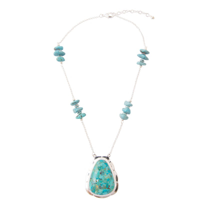 A silver chain necklace featuring a large teardrop-shaped turquoise pendant and smaller turquoise stone bead clusters on the chain, displayed against a solid white background.