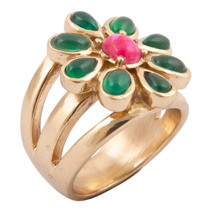 Gold ring with green gemstones and a pink center on a white background