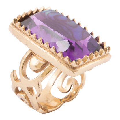 Gold ring with a purple gemstone on a white background