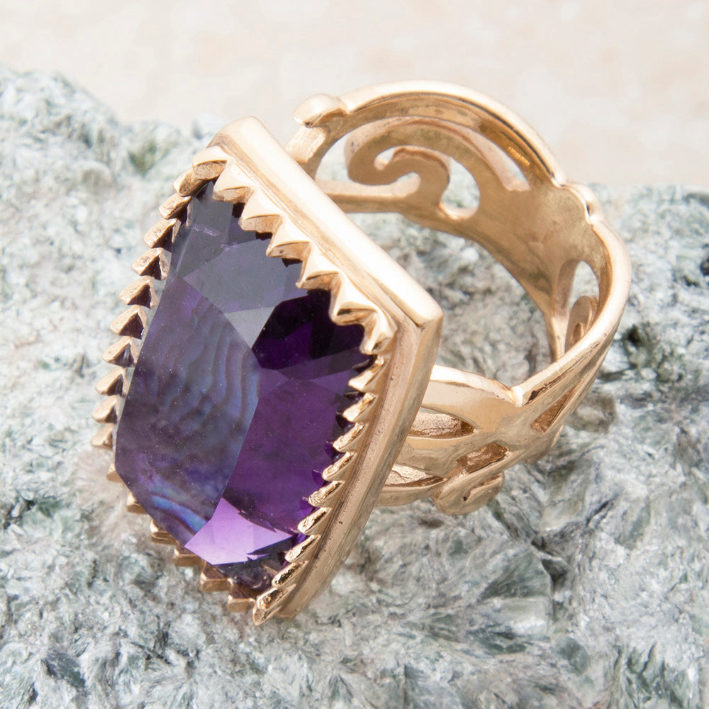 Gold ring with a purple gemstone on a textured surface